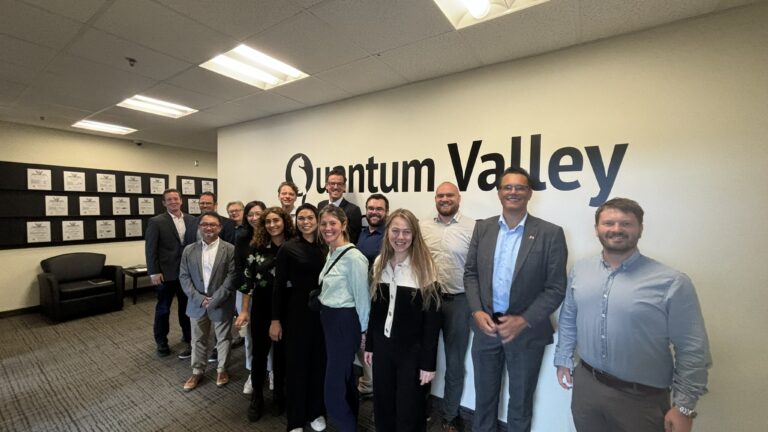 A group of people standing in front of a sign that reads Quantum Valley